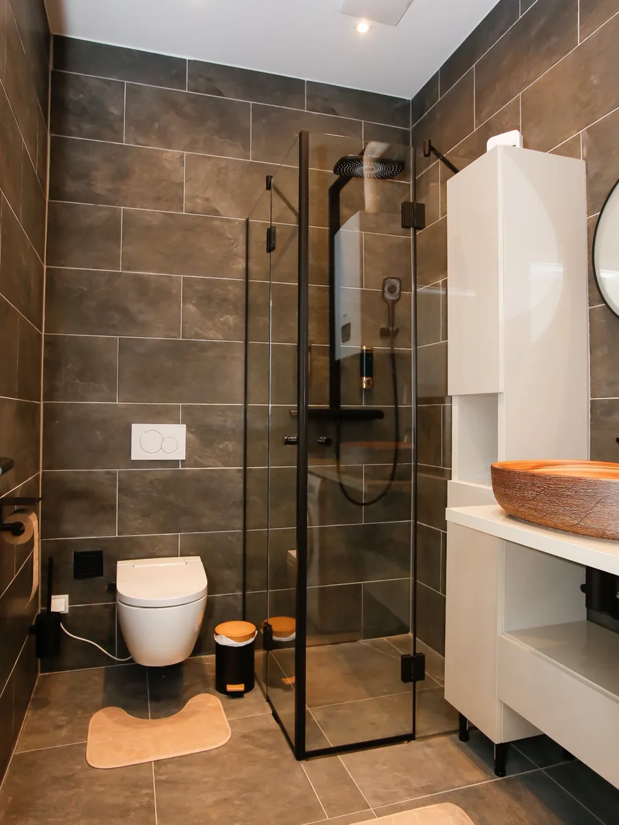Saniertes Badezimmer mit Eckdusche, Wand-WC und anthrazitfarbenen Fliesen